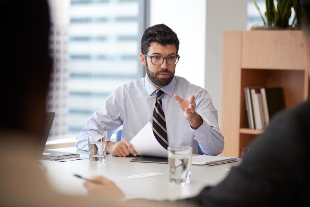 businessman-with-paperwork-sitting-at-table-meetin-4CS8RBG.jpg
